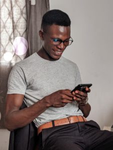 Jeune homme lisant sur l'écran de son smartphone. Les assurances en RDC passent aussi par un usage sur mobile. 